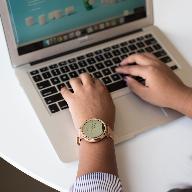 person using MacBook on white table